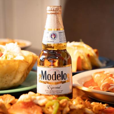 A bottle of Modelo beer and various meals.
