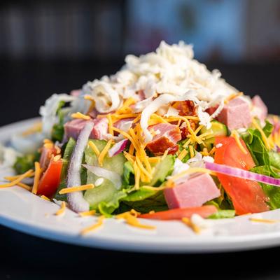 Chef salad with tomatoes, cucumbers, onions, ham, and mozzarella cheese.