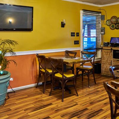 Restaurant interior with wooden chairs and a wall-mounted TV.