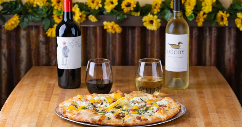 Roasted Peach & Caramelized Pancetta pizza on the table with wines