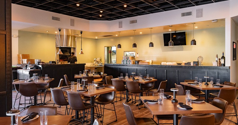 Interior, tables and chairs in dining area with bar behind