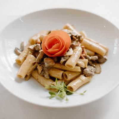 Rigatoni pasta with mushrooms and beef, garnished with a carrot rose.