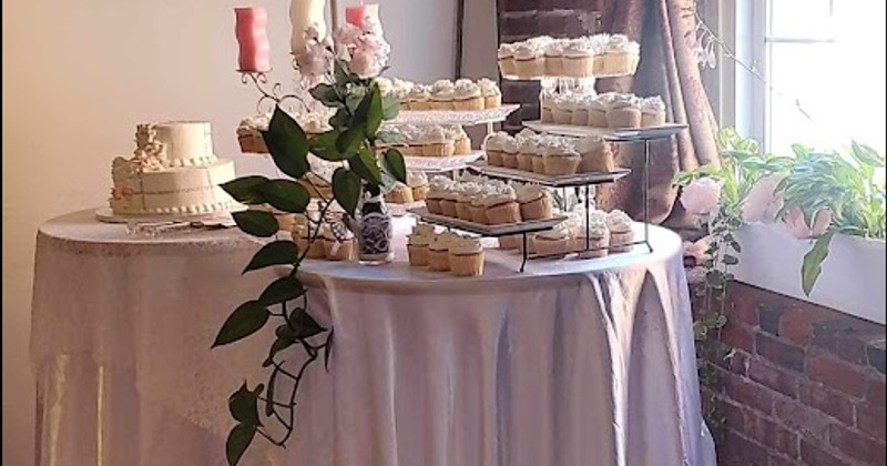 Elegant dessert table with a cake and cupcakes, adorned with flowers and candles