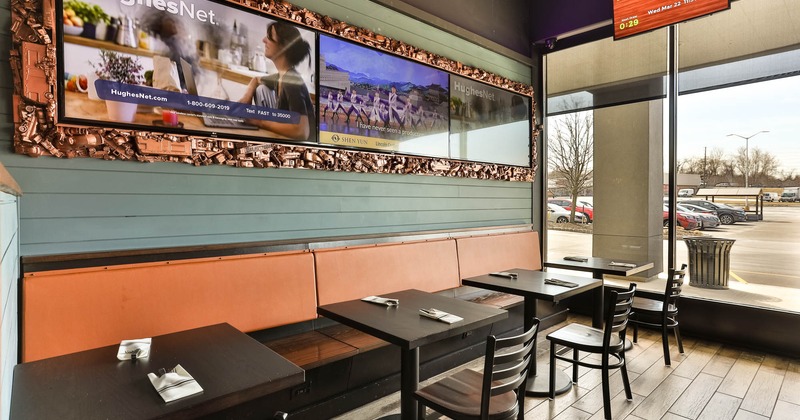 Inside, banquette seating by a wall with tables and chairs, TVs on the wall