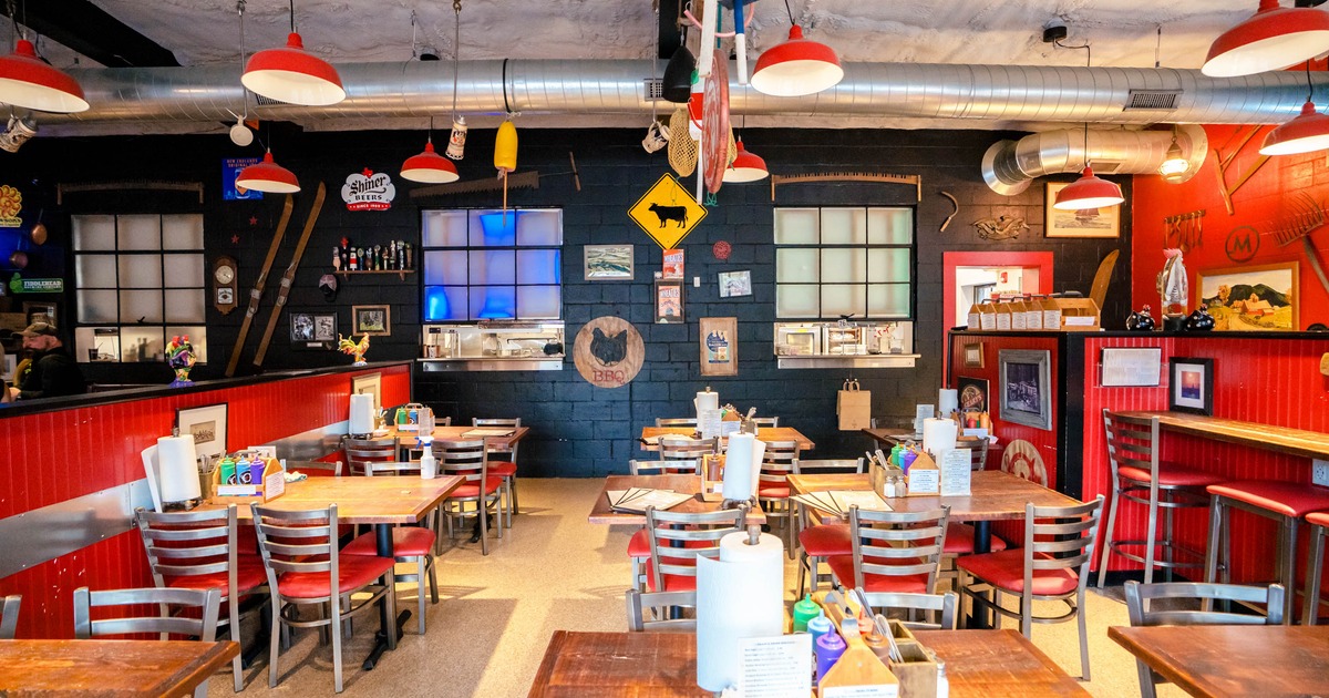 Interior of a barbecue restaurant with red chairs, wooden tables, and vintage decor