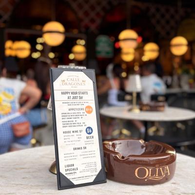 Happy hour menu on a table at the terrace, people in the back at the bar.