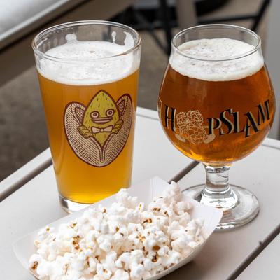 Patio table with two glasses of beer and popcorn.