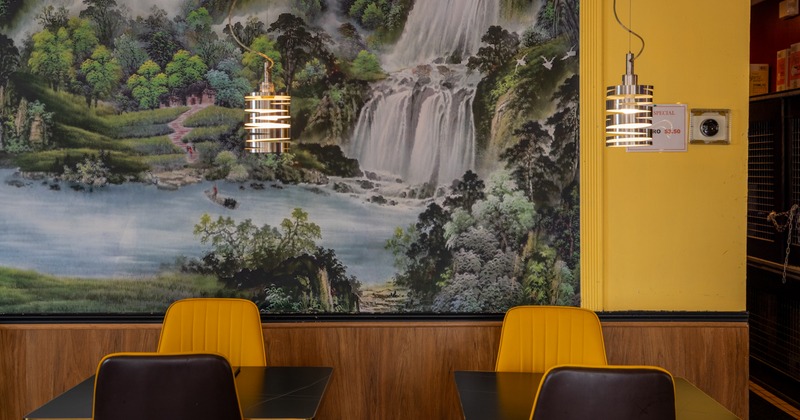 Interior with a mural of a waterfall, tables and chairs and pendant lights