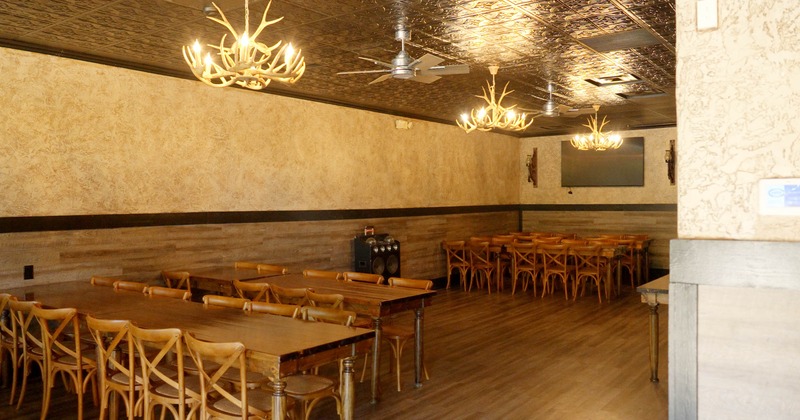 Interior, tables with chairs, speakers, antler chandeliers, wall mounted TV