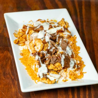 Grilled chicken, steak, bacon, and shrimp served on a bed of rice and topped with queso dip.