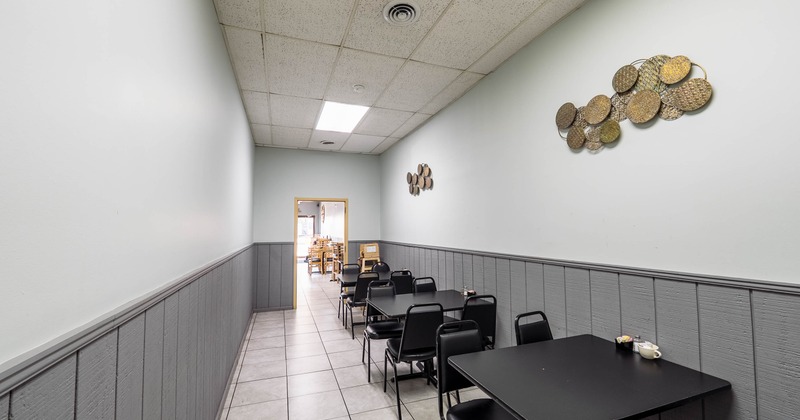 Narrow dining area with black tables and chairs