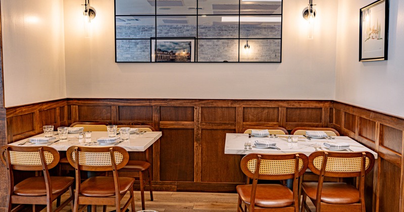 Interior, dining room with wood paneled walls, marble tables set with dishes and glasses