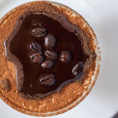 Tiramisu soaked in espresso with coffee beans, mascarpone, and cocoa powder.