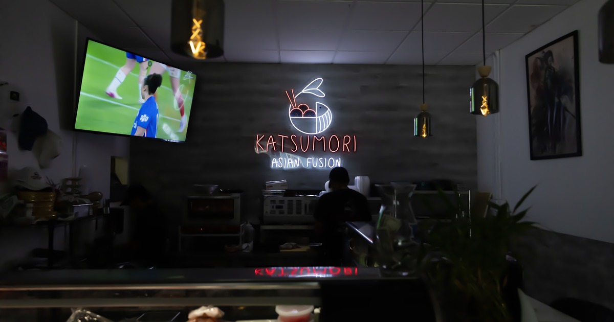 Diner area, tables, chairs, light sign on the wall, tv screen