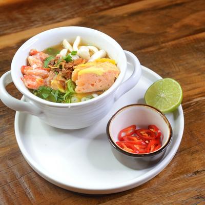 Seafood noodle soup served with red pepper and lime.