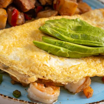 Shrimp Avocado Omelette served with breakfast potatoes.