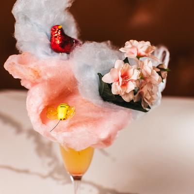 Pink champagne Margarita garnished with cotton candy and decorative flowers.