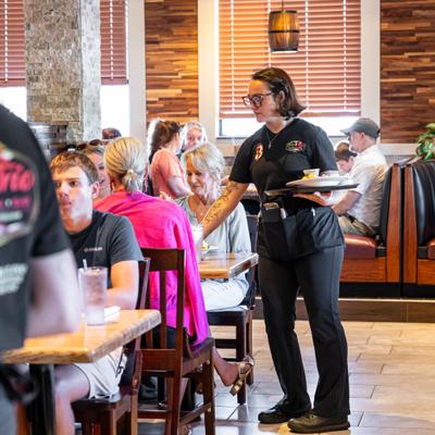 Server delivering food to seated guests.