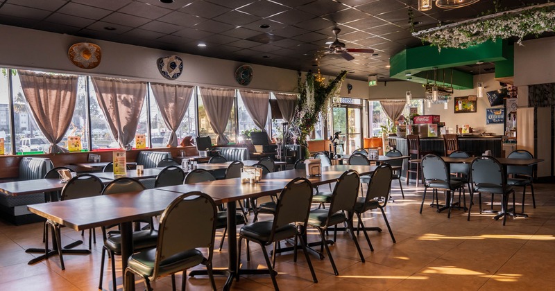 Interior, dining area, long table setup for eight, seating booths, bar, entrance