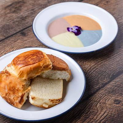 Toasted golden bread rolls served alongside a colorful, four-quadrant sweet dipping custard.