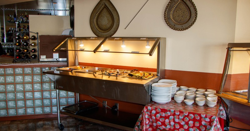 Restaurant buffet setup with food warming stations and stacked plates
