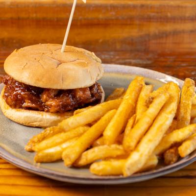 Pulled pork sandwich with BBQ sauce and fries.