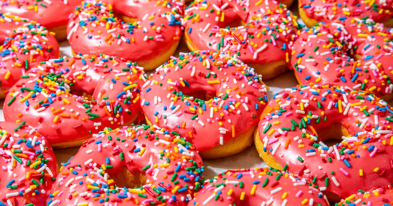 Pink frosted donuts covered in rainbow sprinkles