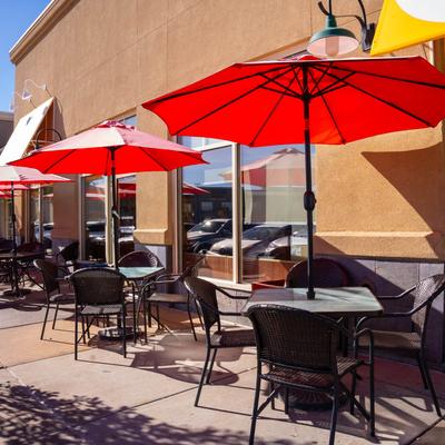 Outdoor seating area with tables and parasols.