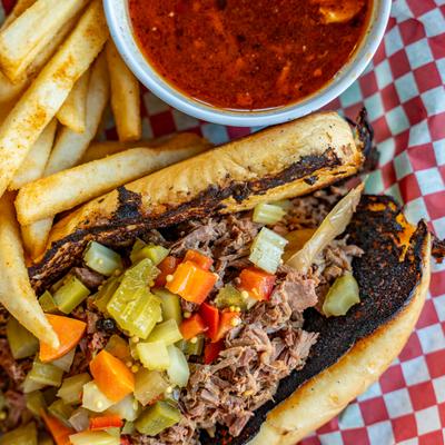 The Italian Beef served with au jus for dipping and fries, top view, close up.