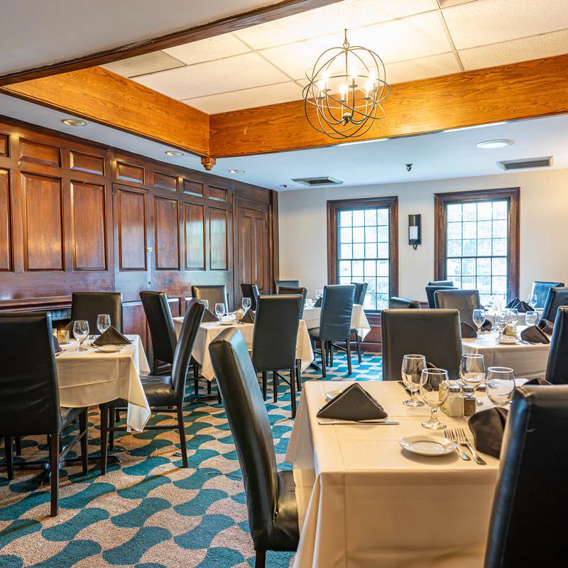 Elegant restaurant dining room with set tables and wood-paneled walls