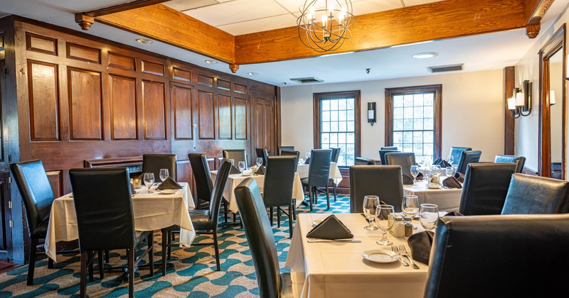Elegant restaurant dining room with set tables and wood-paneled walls