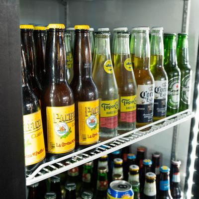 Refrigerator shelves stocked with various bottles of beer and hard seltzer.