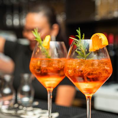 Two Aperol Spritz cocktails on a bar counter.