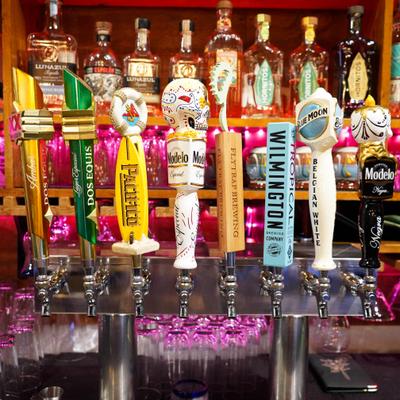 View at the beer taps with drink shelves in the background.