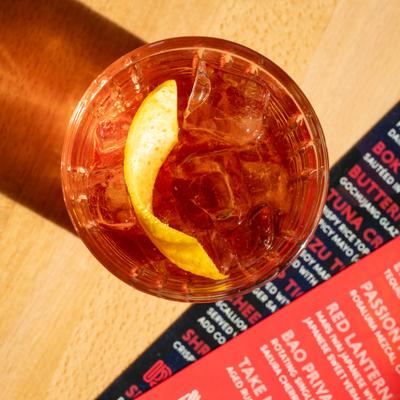 Red Lantern cocktail garnished with a lemon peel, overhead view.