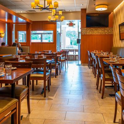 Dining room, wooden tables and chairs, set with glasses, and warm lighting.