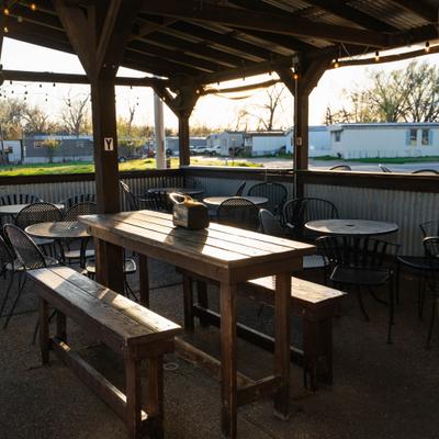 Covered patio dining area featuring wooden communal tables and benches.