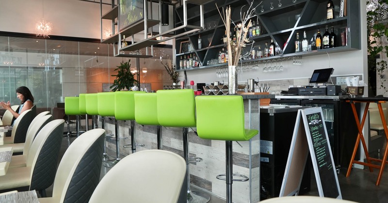 Interior of a modern bar area with lime green stools and stocked shelves