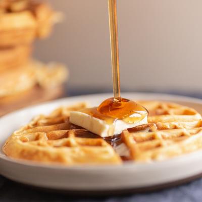 Waffle with butter on top, honey dripping over it.