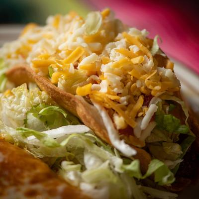 Taco with lettuce, tomato, and shredded cheese.