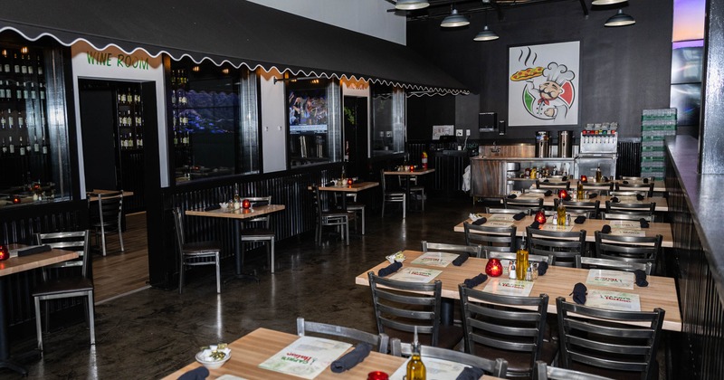 Interior - wooden tables, black napkins, olive oil bottles;  a "Wine Room" and a chef mural