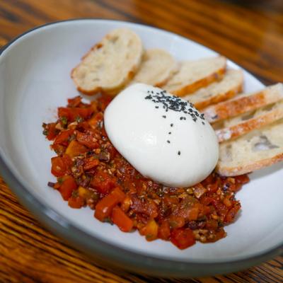 Burrata atop stone fruit chutney, served with bread slices.
