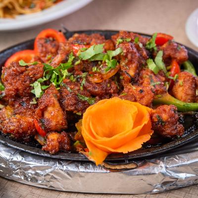 Chili Chicken garnished with herbs and carved carrot flower.