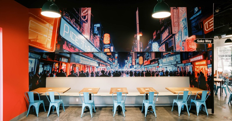 Interior, long banquette bench with tables and chairs, large mural of the city on the wall