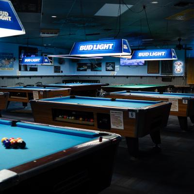 Interior featuring multiple pool tables and branded lighting fixtures.
