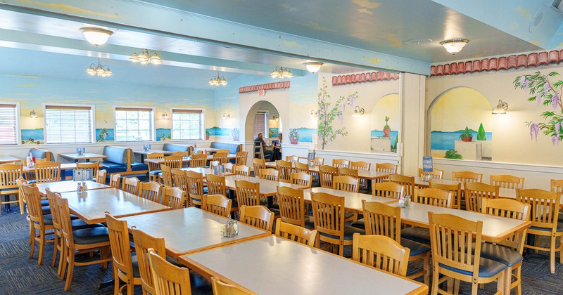 Restaurant interior with wooden tables, chairs, and murals