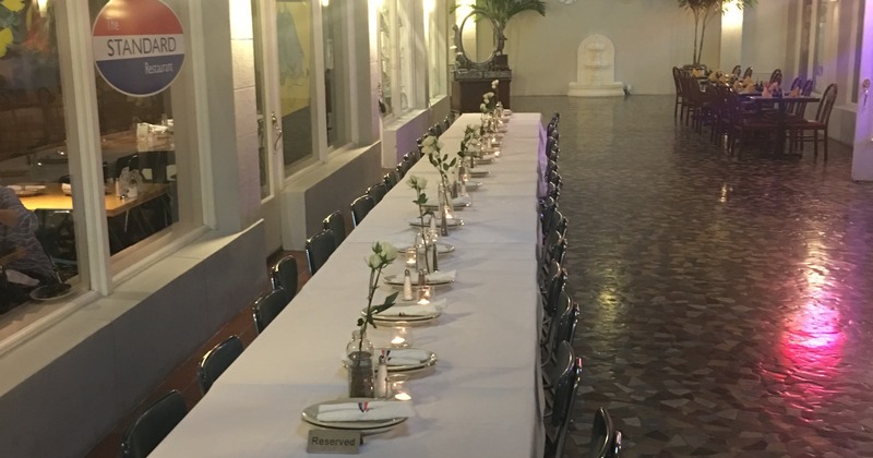 A long table with chairs, white tablecloth, tableware, candle light, and flowers