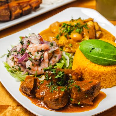 Beef chunks in sauce, served with yellow rice, tripe stew, and shrimp ceviche.