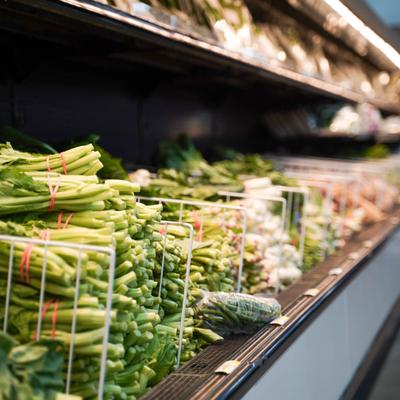 Leafy greens and garlic are neatly displayed in wire baskets at the produce section.