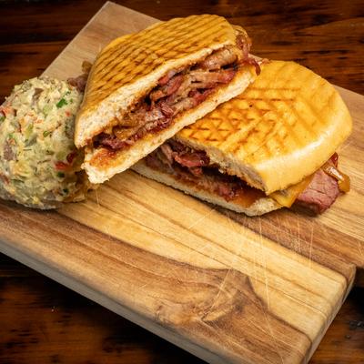 Smoked tri tip sandwich, with BBQ sauce, caramelized onions, and potato salad.